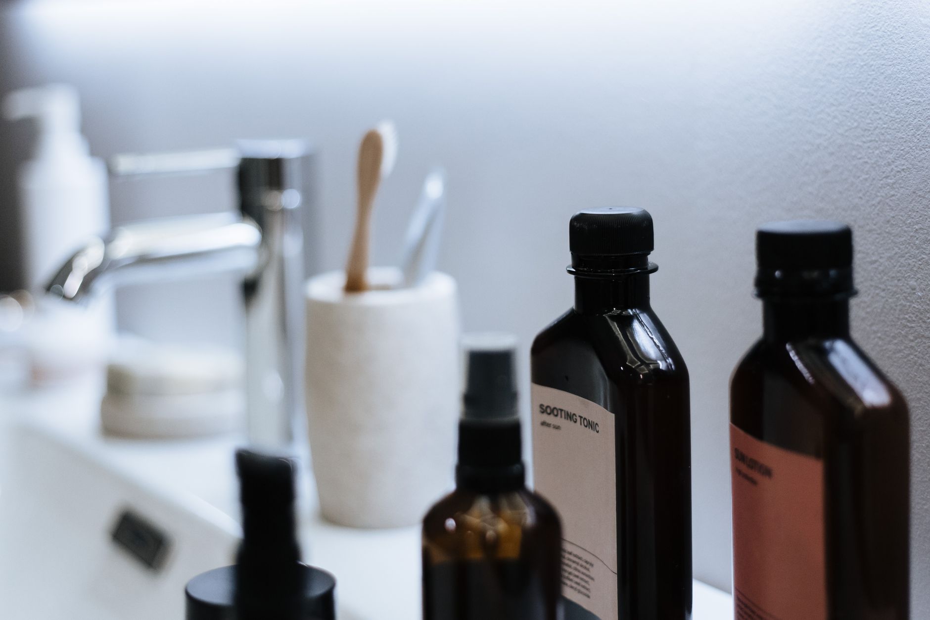 Banyo lavabosu kenarında düzenli şekilde dizilmiş saç ve cilt bakım ürünleri