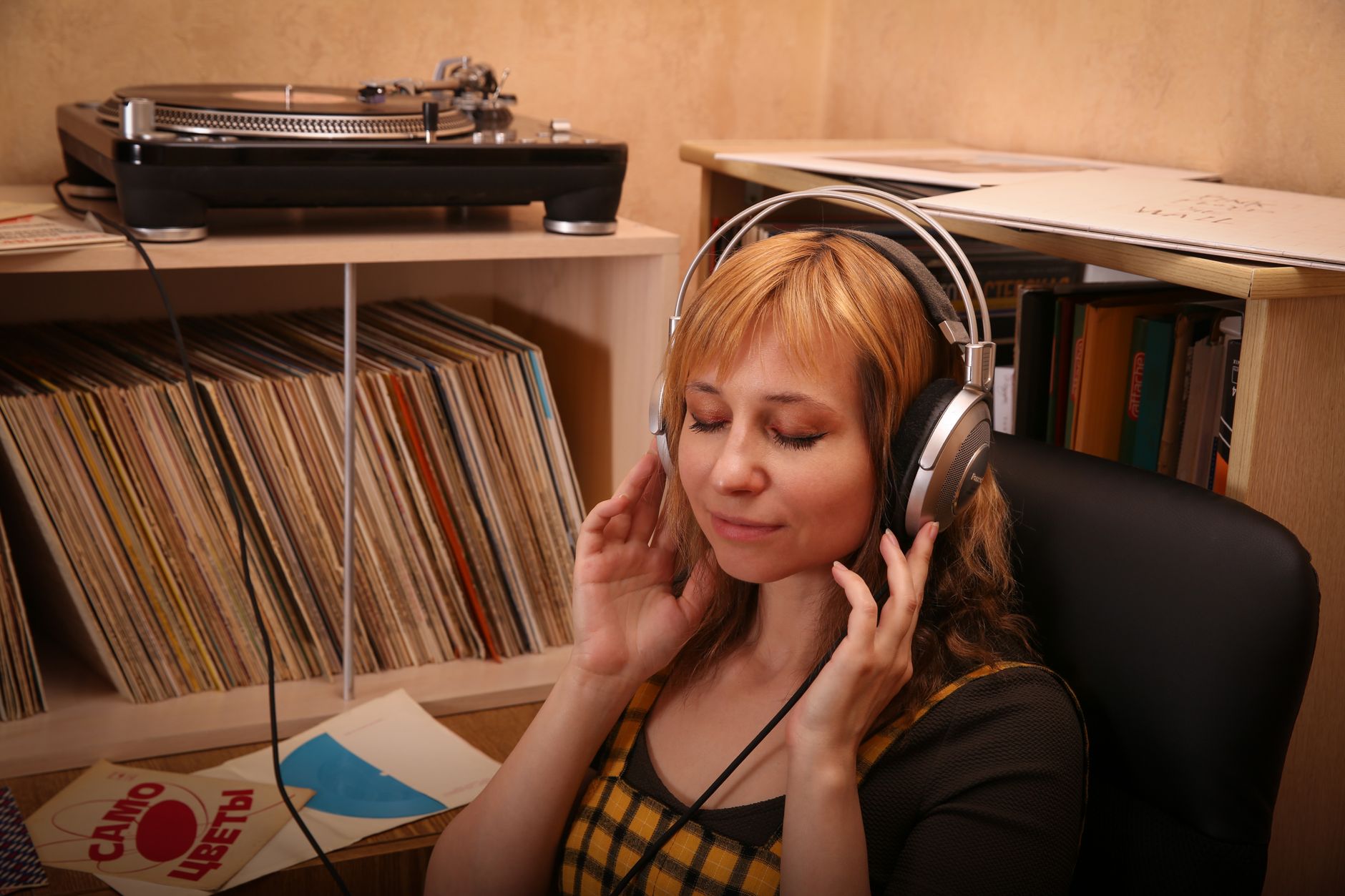 Plak rafının önünde kulaklıkla müzik dinleyen kadın