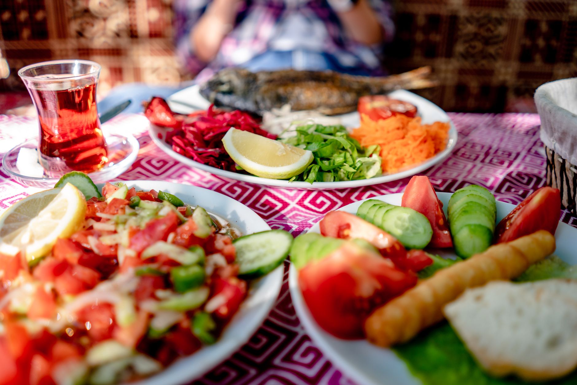 Sofrada ızgara balık, taze salata ve çay içeren bir Akdeniz öğünü