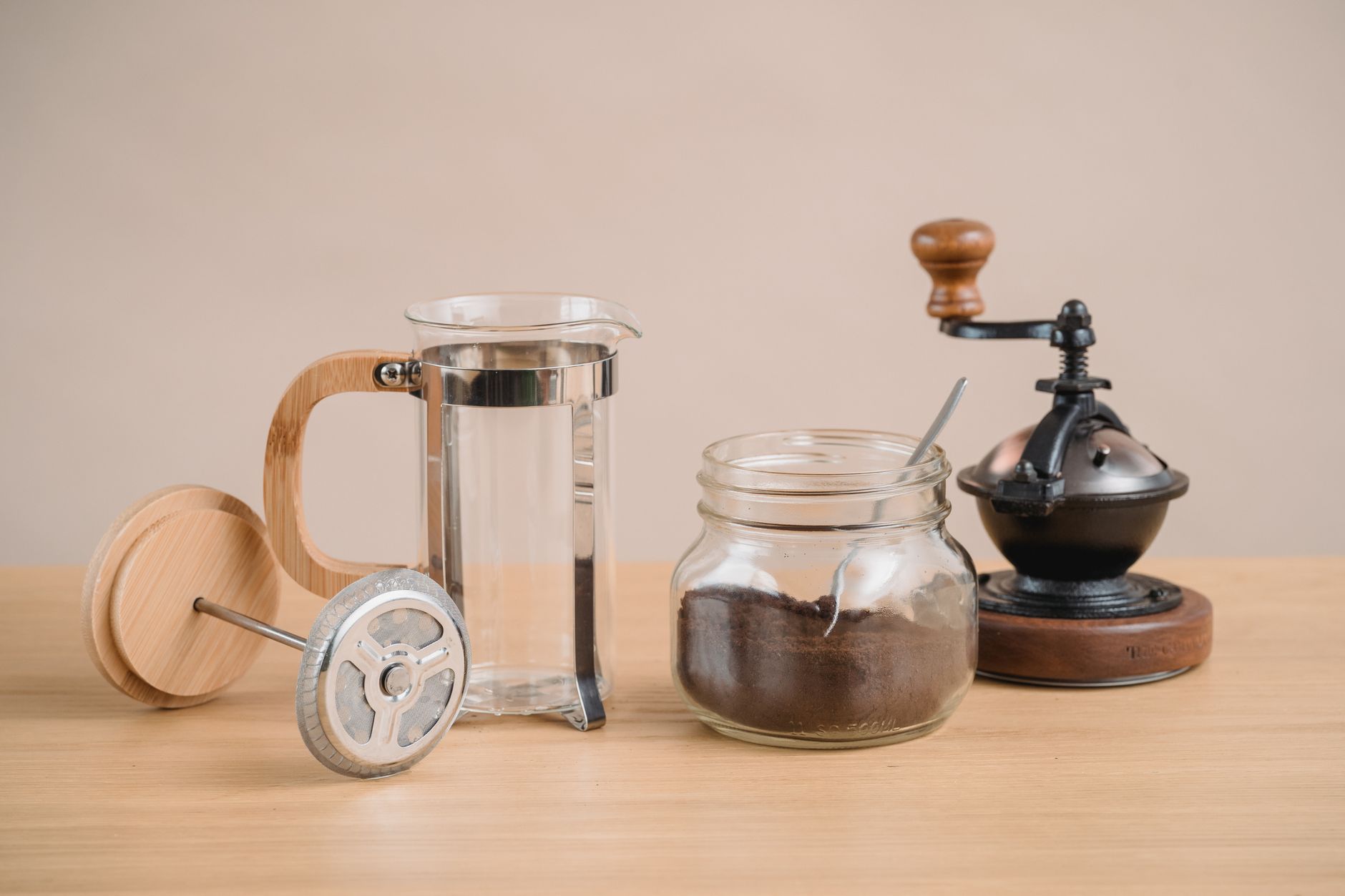 Ahşap tezgâhta French press, değirmen ve öğütülmüş kahve