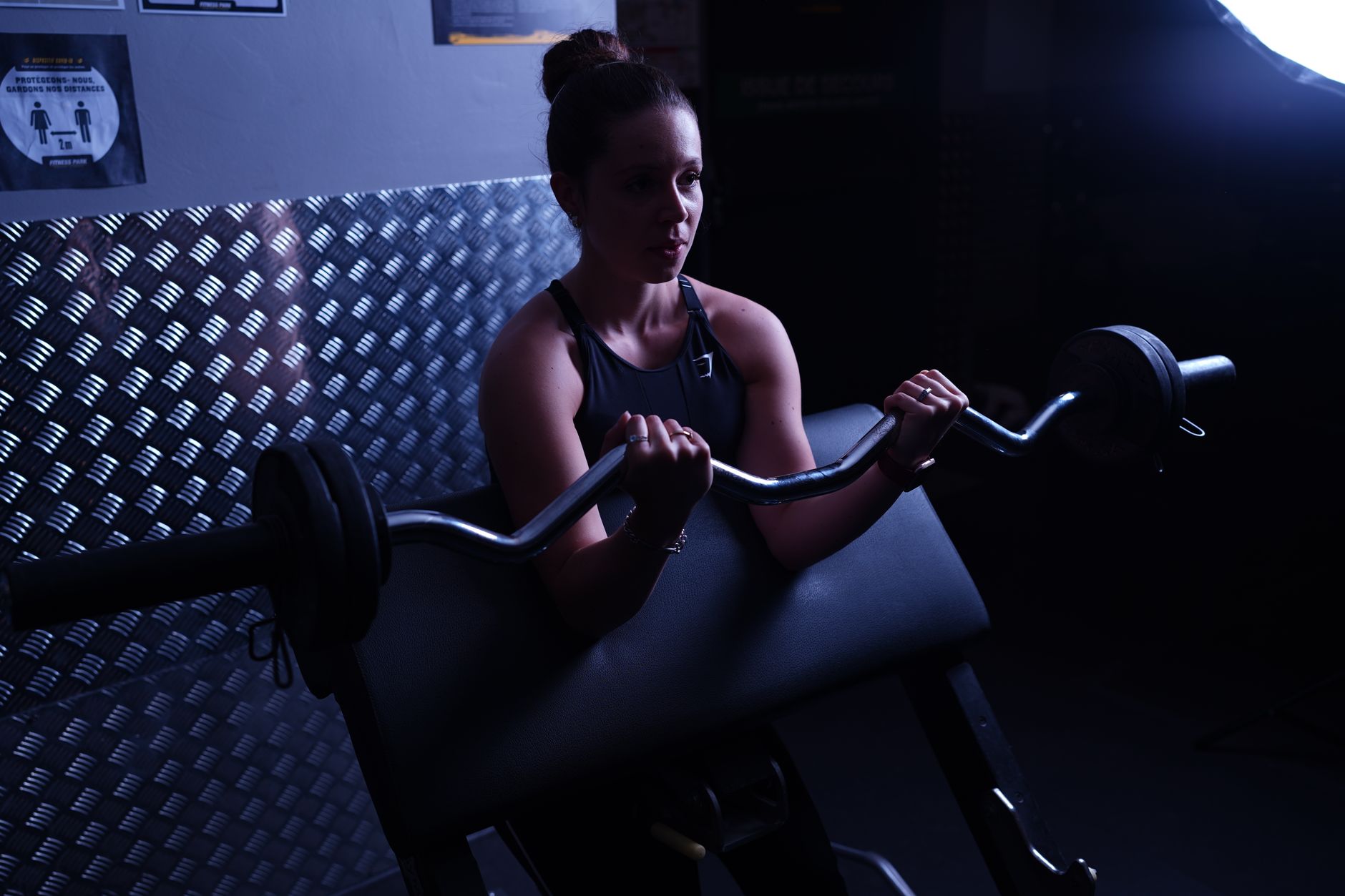 Loş bir spor salonunda ağırlık kaldıran kararlı bir kadın
