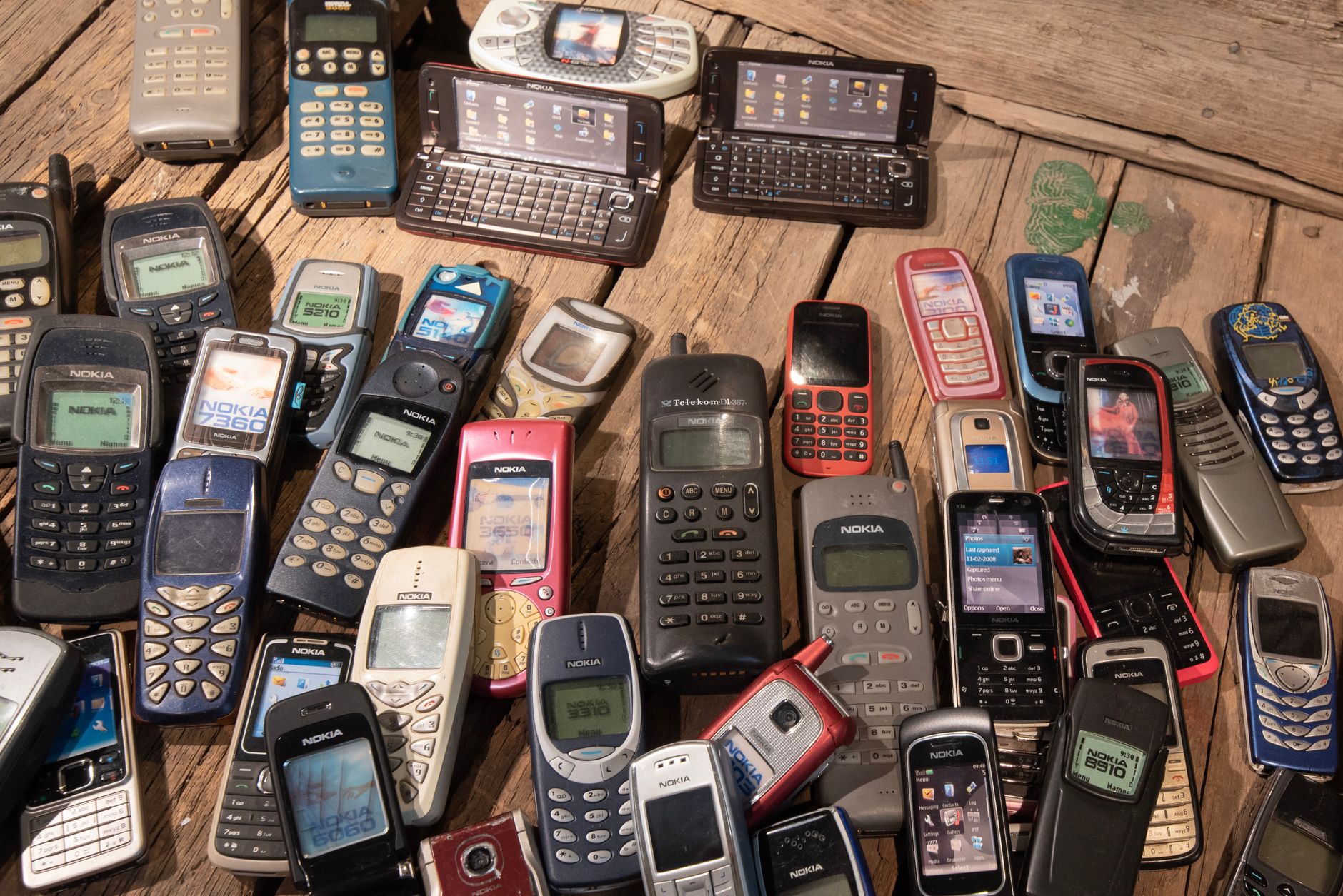 Ahşap zemin üzerinde dizilmiş çok sayıda eski cep telefonu
