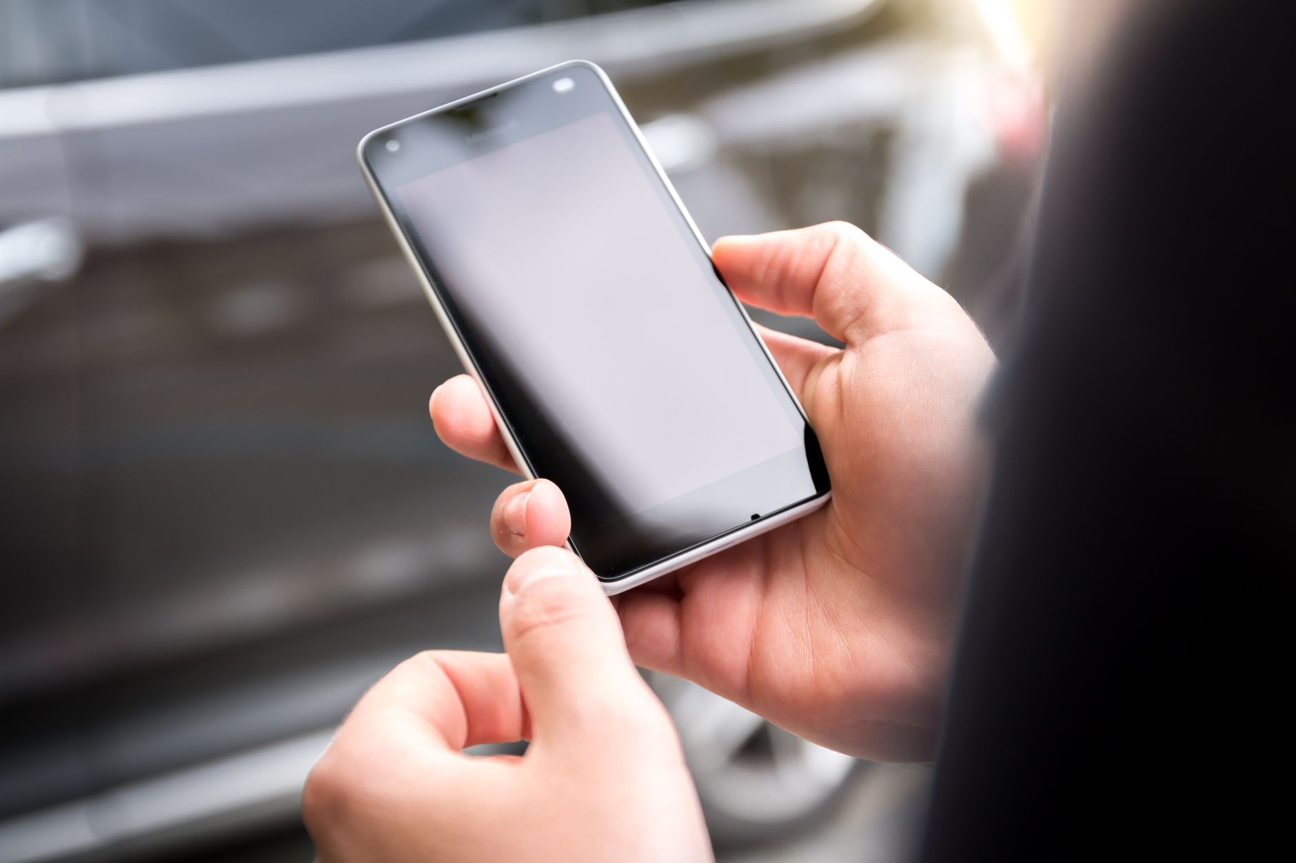 Bir elin disarida akilli telefon ekranina dokunarak ayar yaptigi yakin cekim