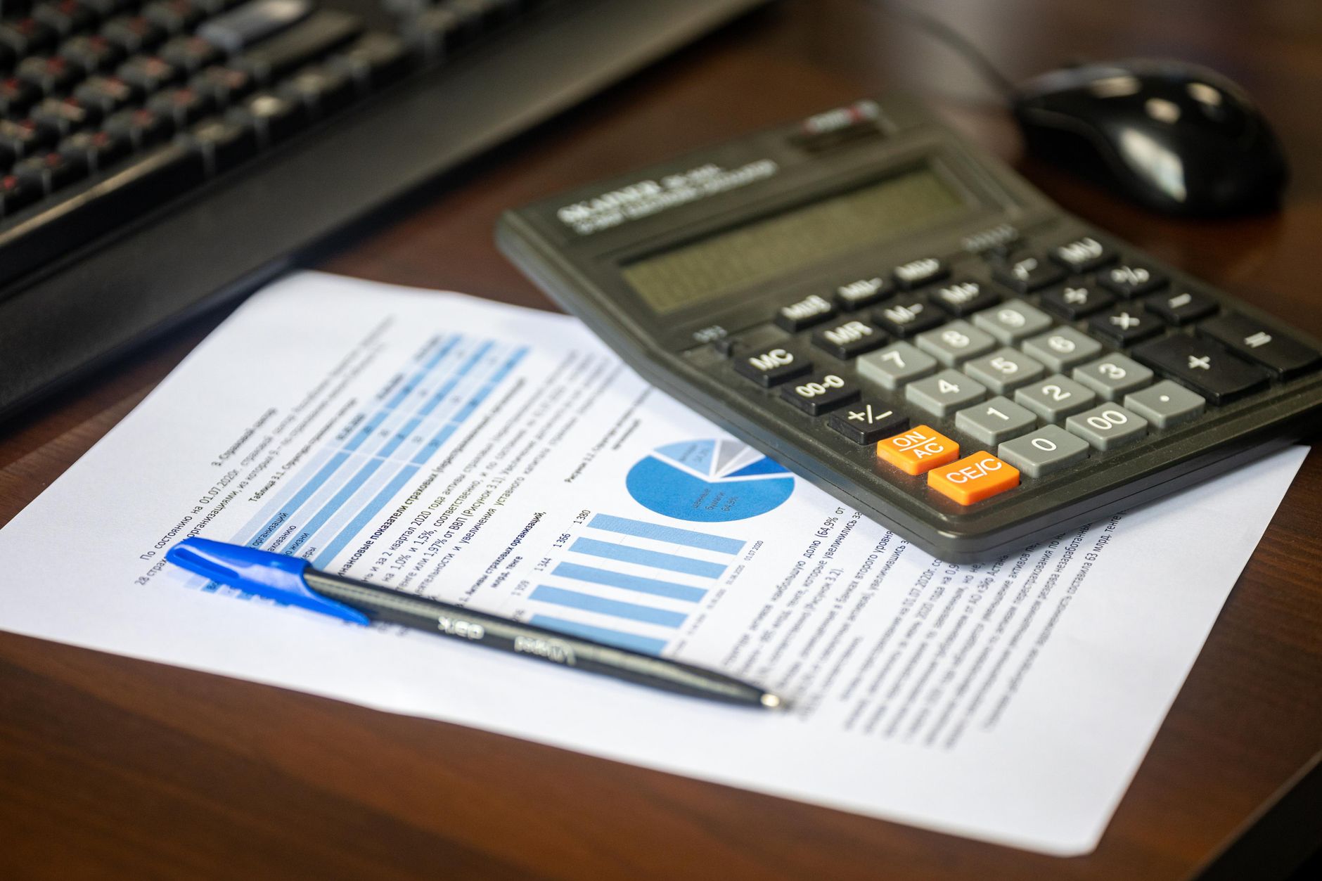 Üzerinde hesap makinesi, kalem ve finansal rapor bulunan çalışma masası