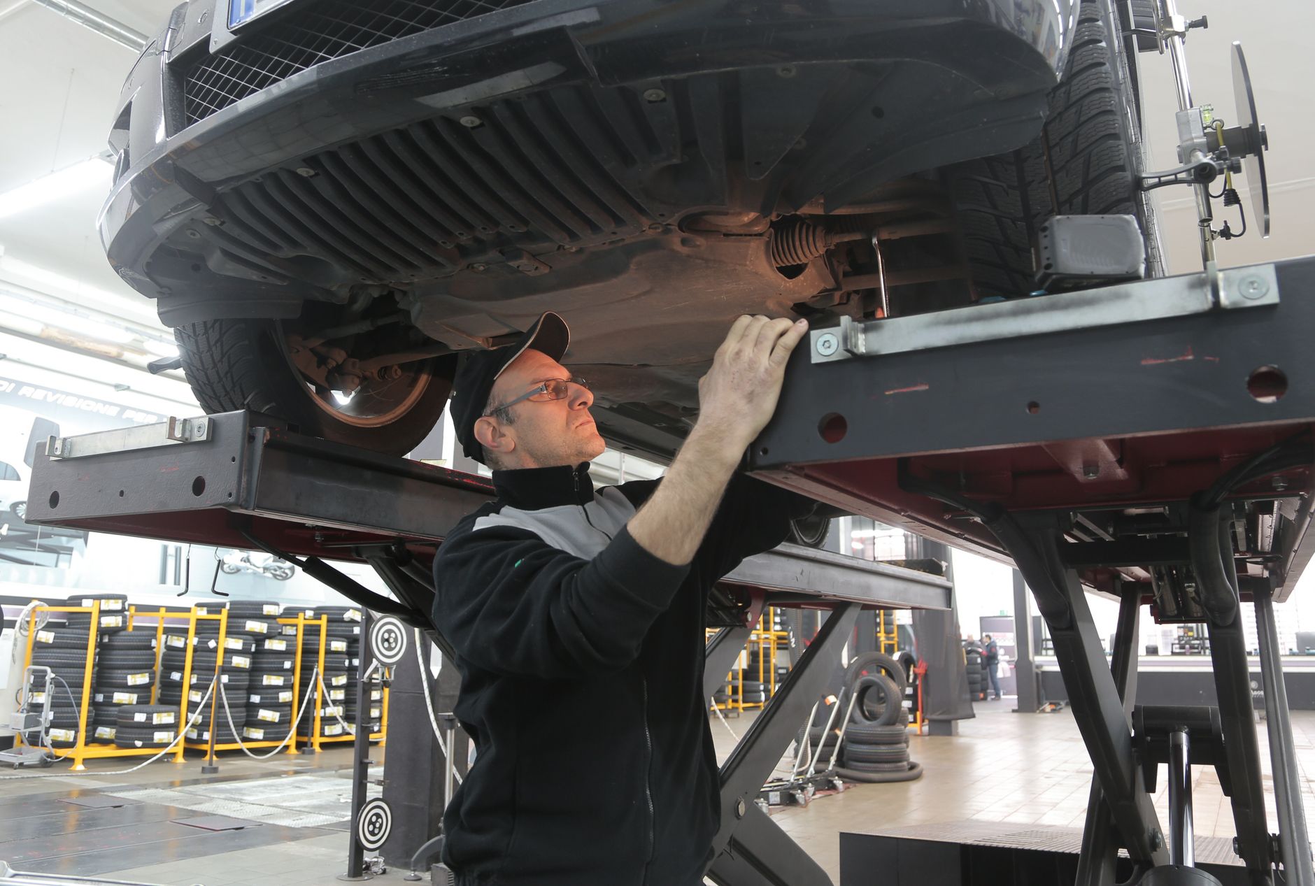 Servis liftine kaldırılmış bir aracın altını inceleyen tamirci