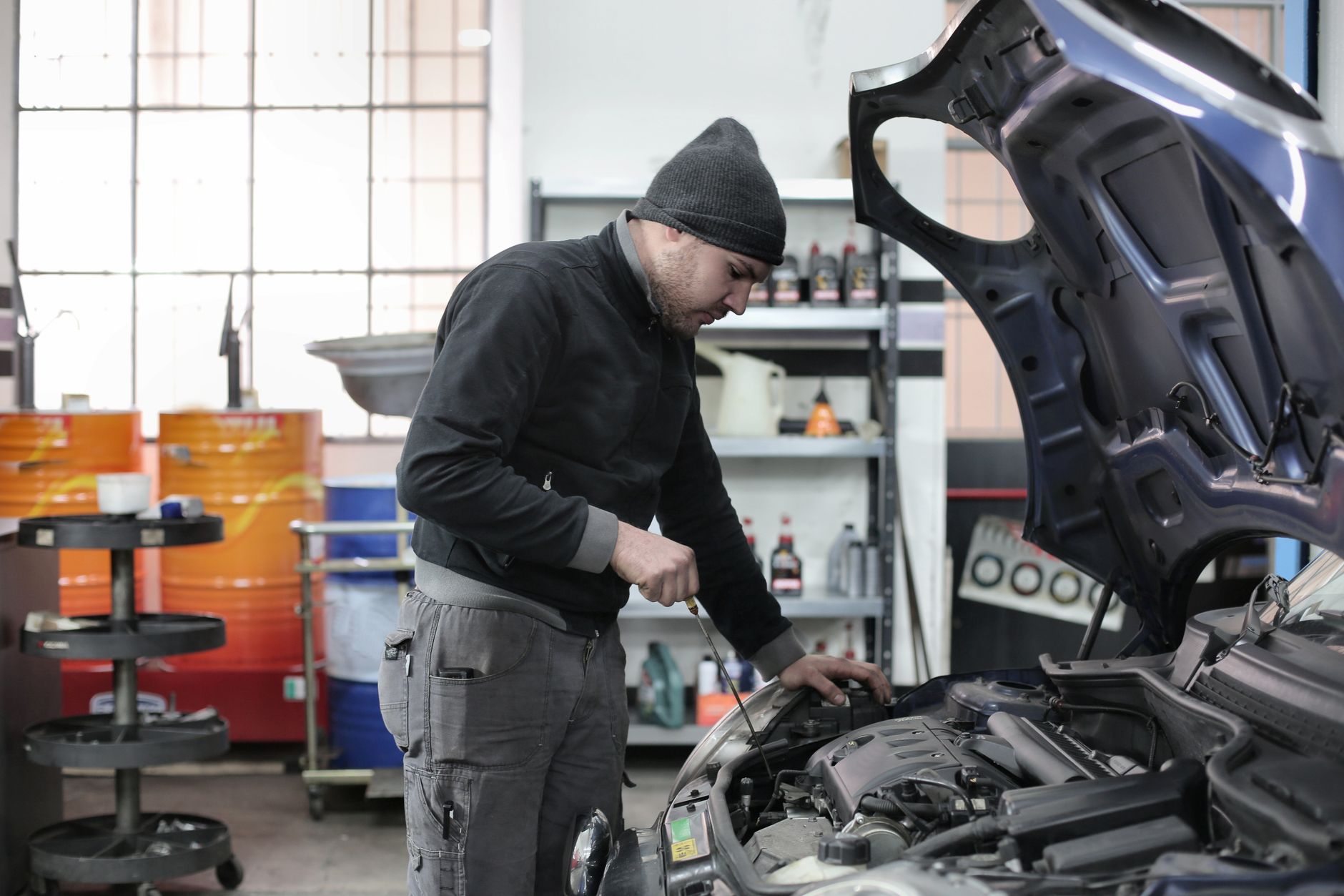 Bir tamirci serviste açık kaputun altında motoru kontrol ediyor