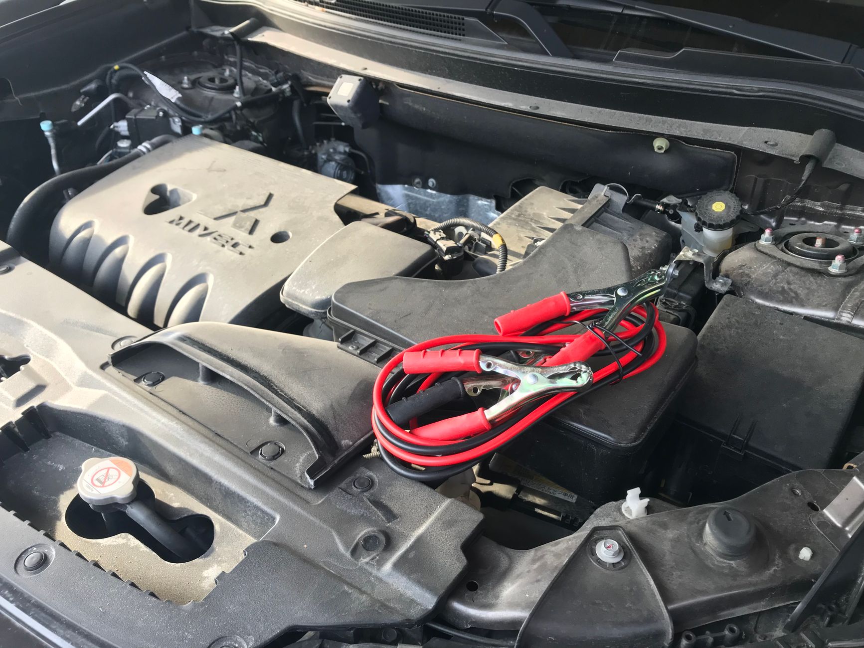 Açık motor kaputunun altında aküye bağlanmış takviye kabloları