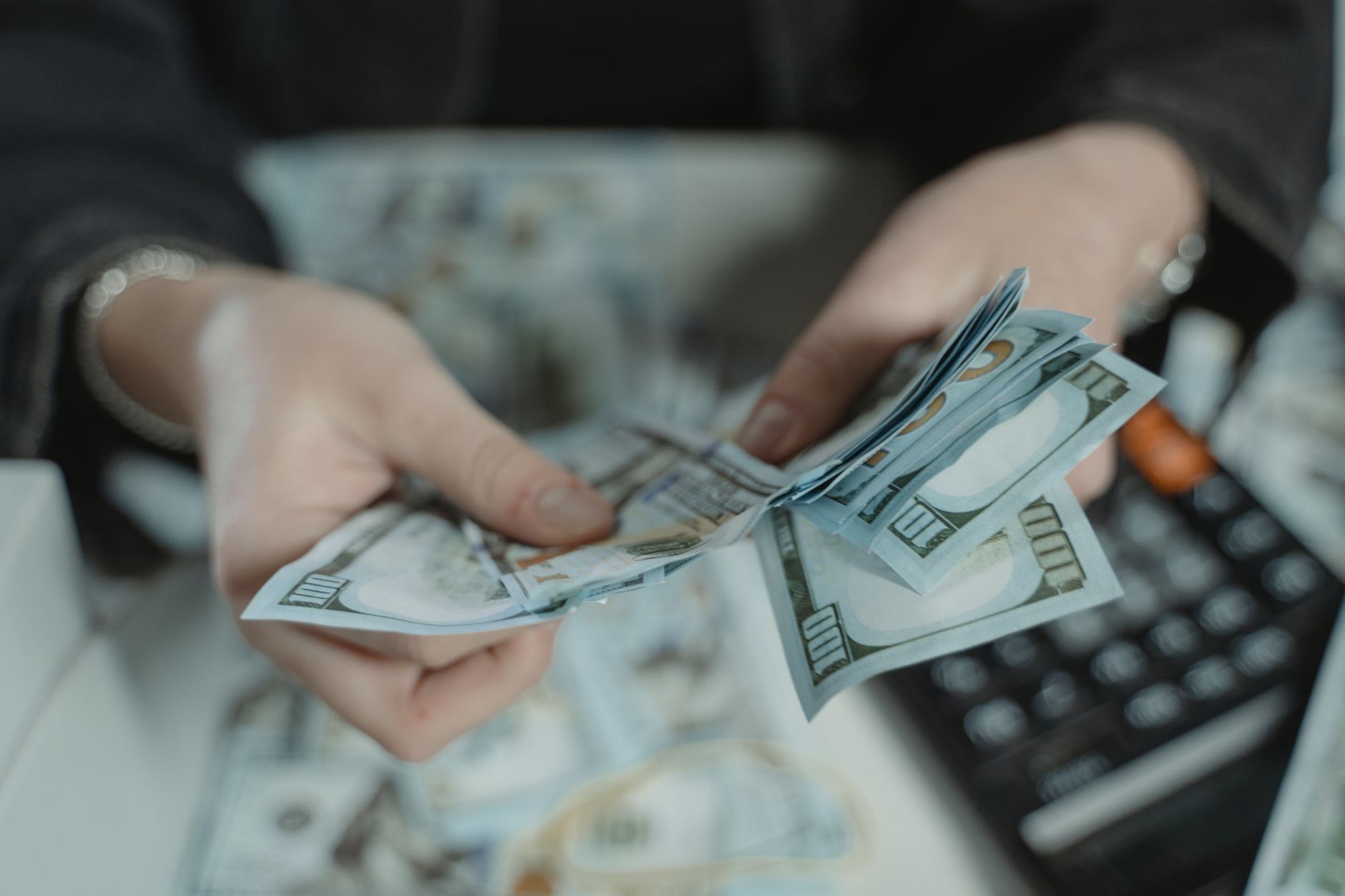 Bir kişinin hesap makinesi önünde elindeki banknotları sayması
