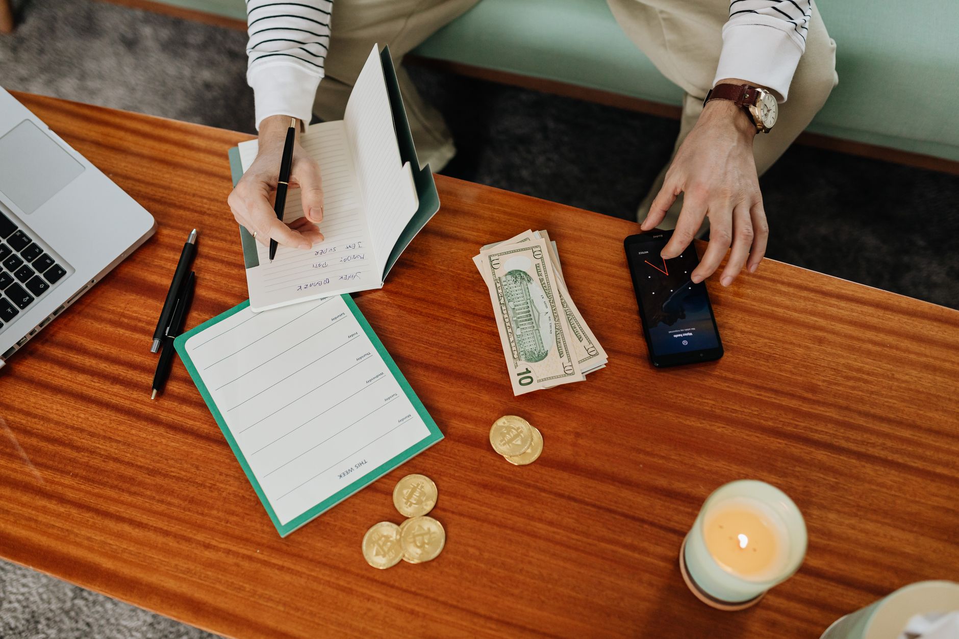 Bir defter üzerine finansal plan yazan ve para hesaplayan bir kişi