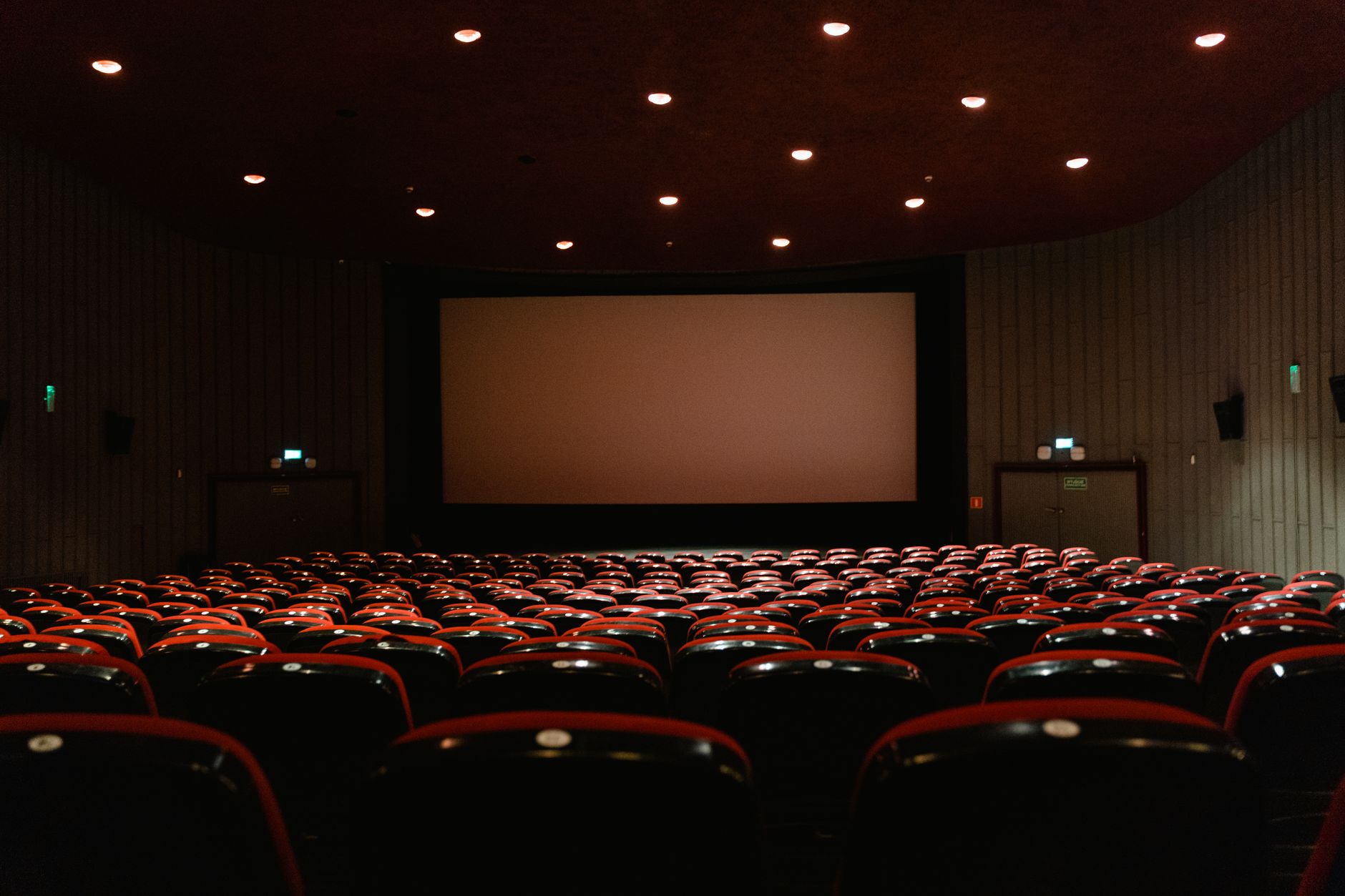 Loş ışıklı boş bir sinema salonu ve aydınlanmış perde