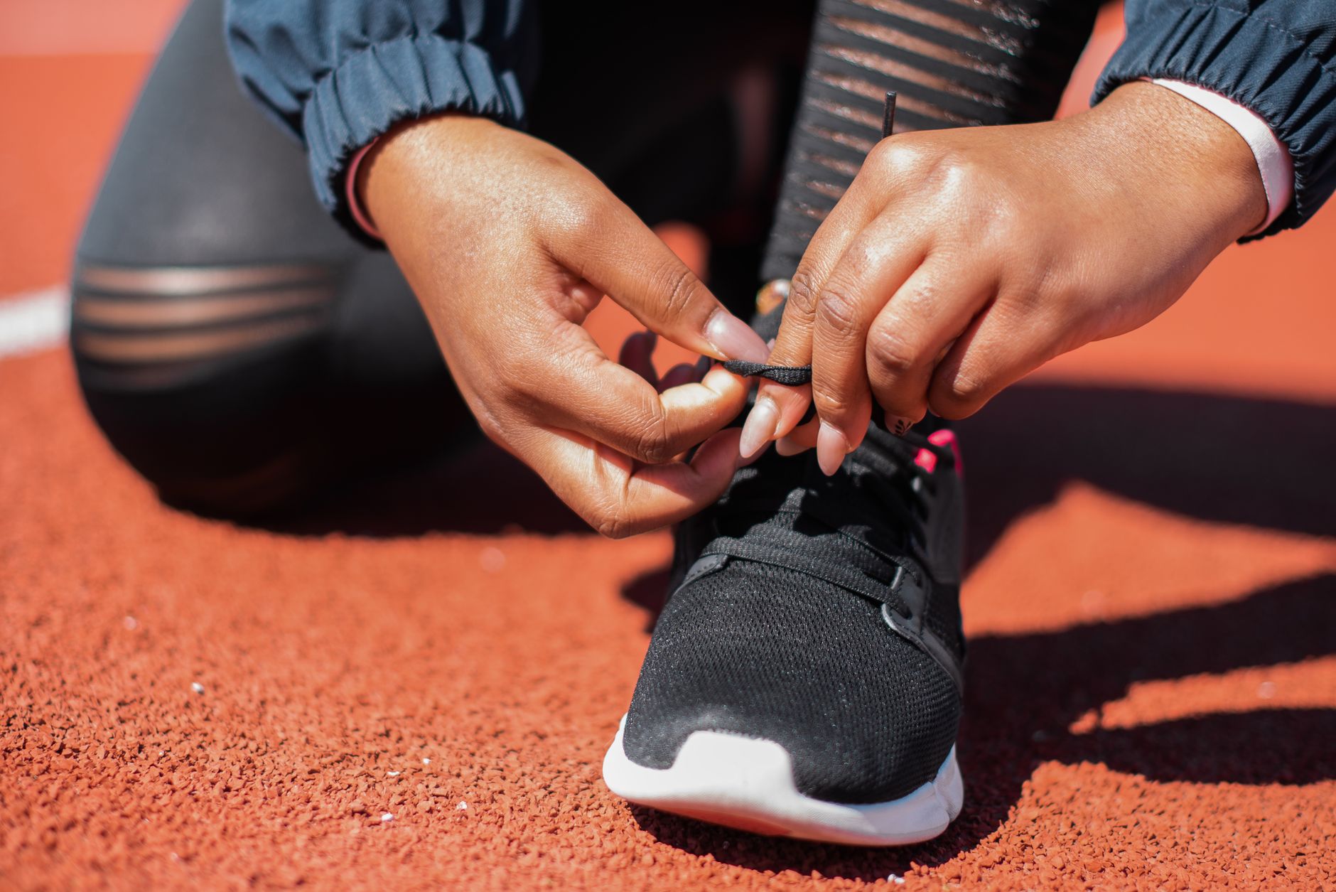 Koşu pistinde spor ayakkabısının bağcıklarını bağlayan bir sporcu