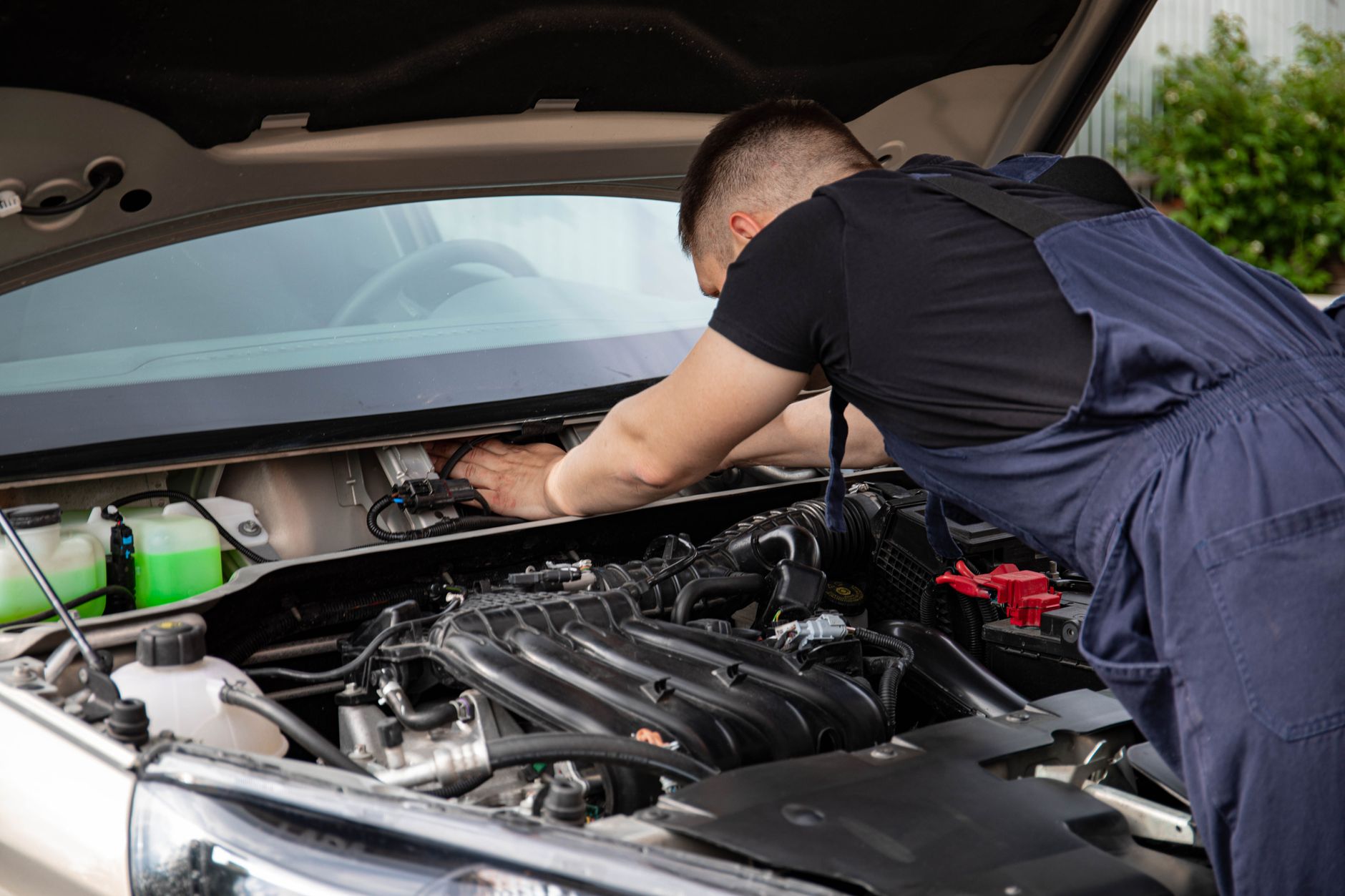 Bir tamirci açık kaput altında motor üzerinde çalışıyor